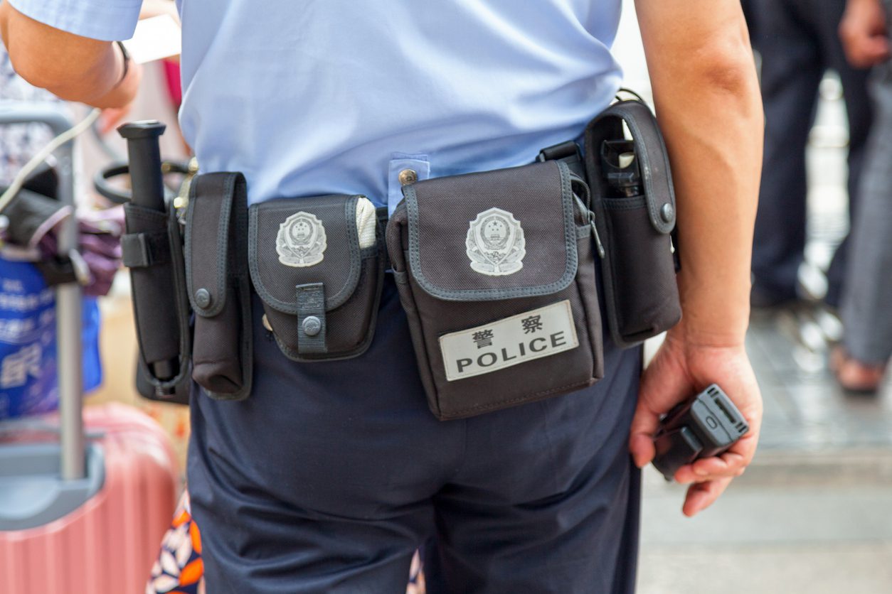 Close-up on the belt of a Chinese police officer in Beijing displaying the coat of arms of China.